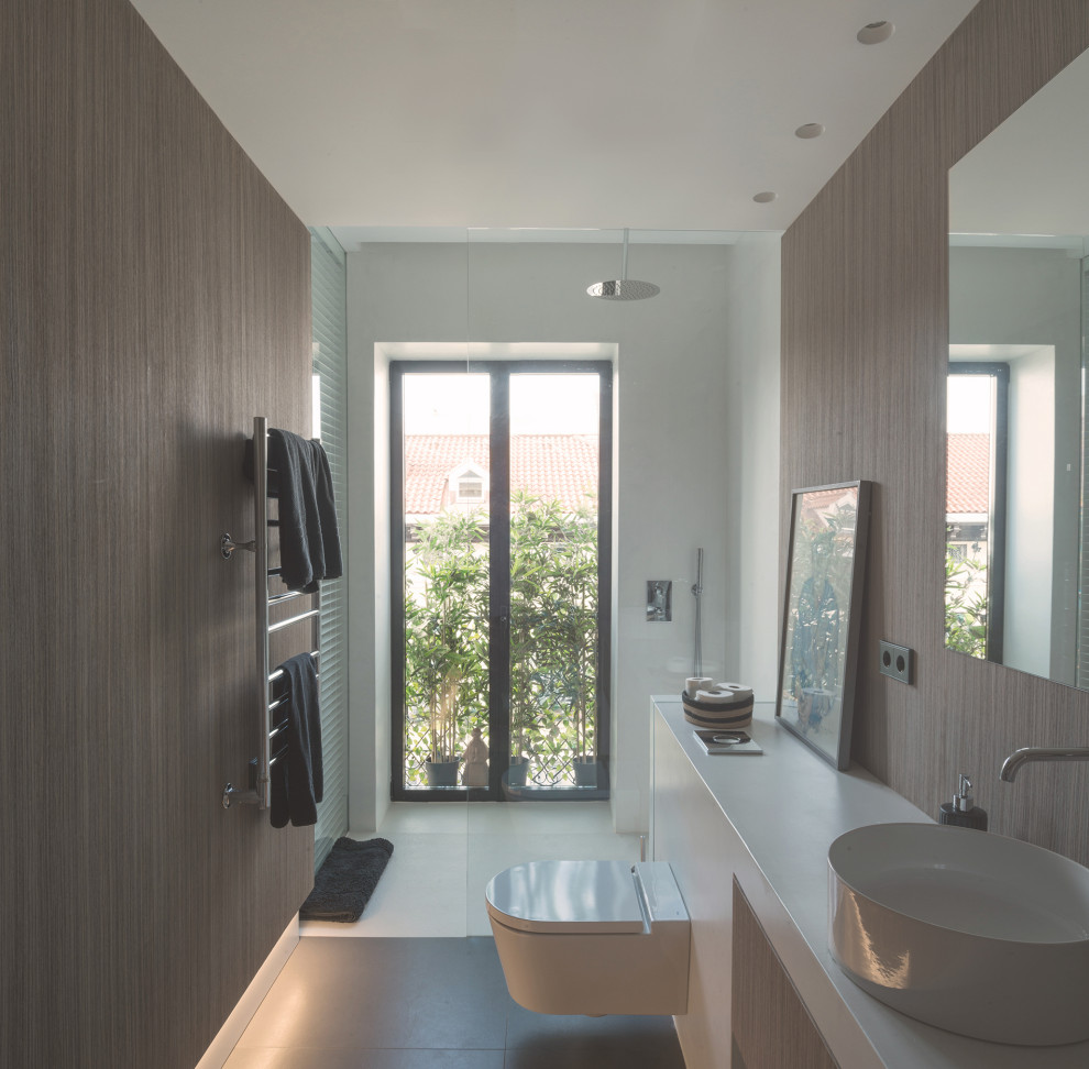 This is an example of a large contemporary master bathroom in Madrid with furniture-like cabinets, white cabinets, a curbless shower, a bidet, white walls, porcelain floors, concrete benchtops, grey floor, white benchtops, a single vanity, a floating vanity and decorative wall panelling.