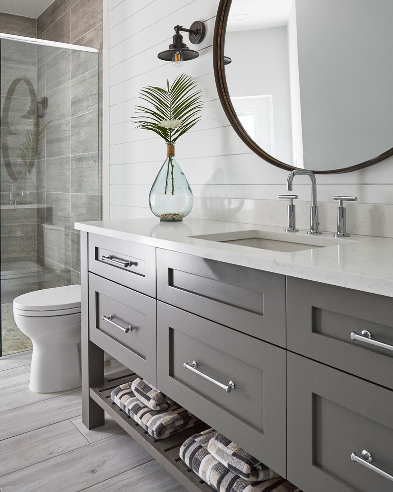 Inspiration for a mid-sized beach style 3/4 bathroom in Other with shaker cabinets, grey cabinets, an alcove shower, a two-piece toilet, white tile, wood-look tile, white walls, wood-look tile, a wall-mount sink, engineered quartz benchtops, grey floor, a hinged shower door, grey benchtops, a single vanity and a freestanding vanity.