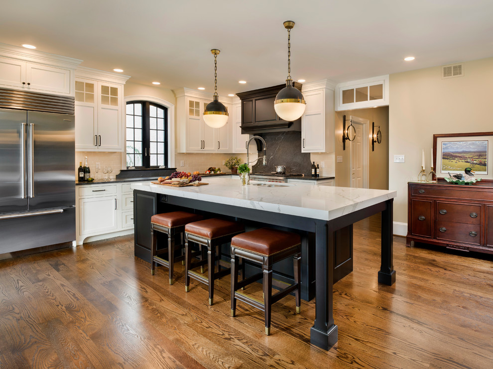 Design ideas for a traditional l-shaped kitchen in Wilmington with an undermount sink, shaker cabinets, black splashback, stainless steel appliances, medium hardwood floors, with island and black benchtop.