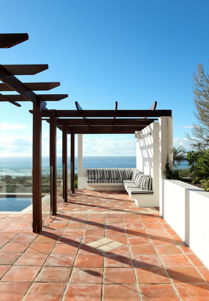 Photo of a mediterranean backyard patio in Sunshine Coast with tile and a pergola.