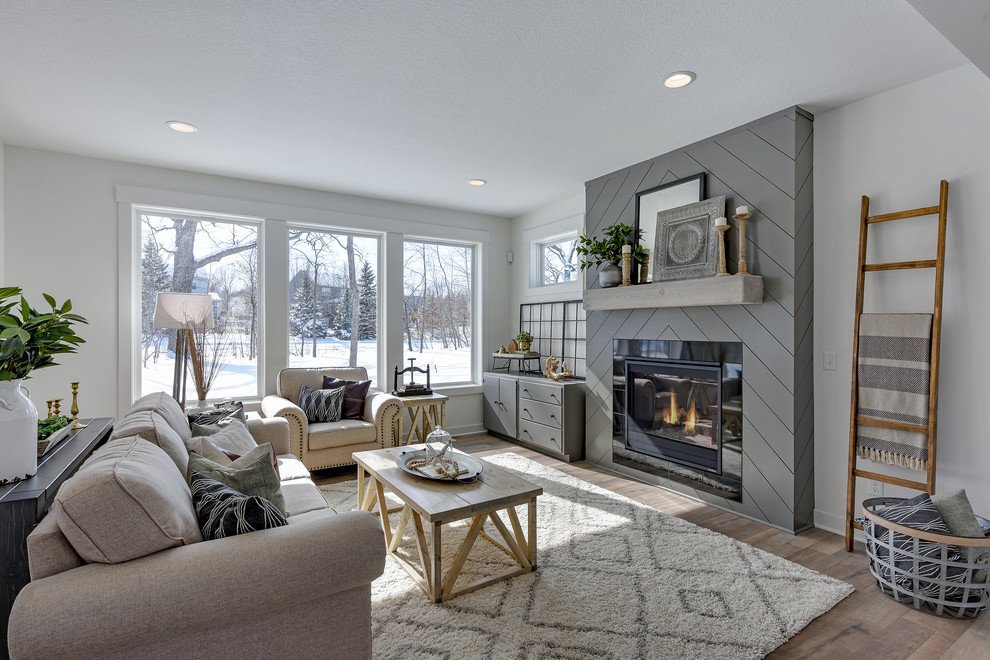 Mid-sized country open concept living room in Minneapolis with white walls, laminate floors, a standard fireplace, a tile fireplace surround, no tv and grey floor.