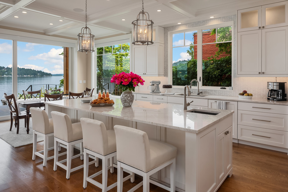 Mid-sized transitional single-wall separate kitchen in Seattle with an undermount sink, shaker cabinets, white cabinets, granite benchtops, beige splashback, mosaic tile splashback, stainless steel appliances, medium hardwood floors, with island and white benchtop.