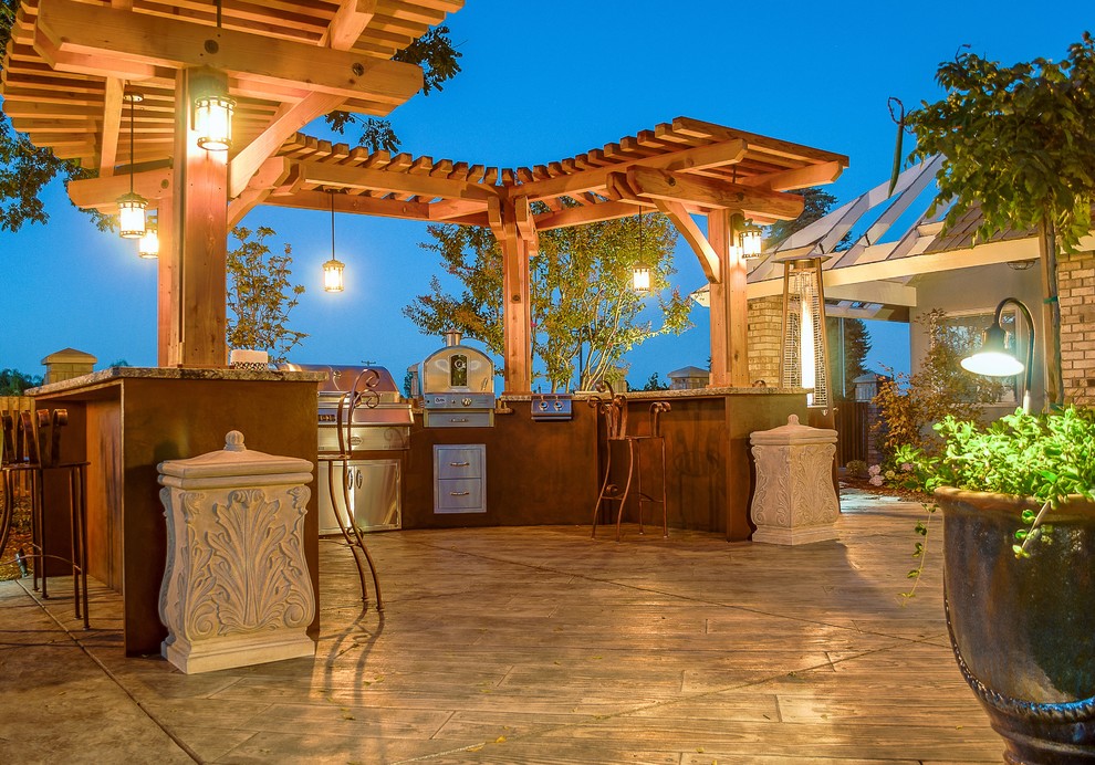 Patio kitchen - huge rustic backyard stone patio kitchen idea with a pergola