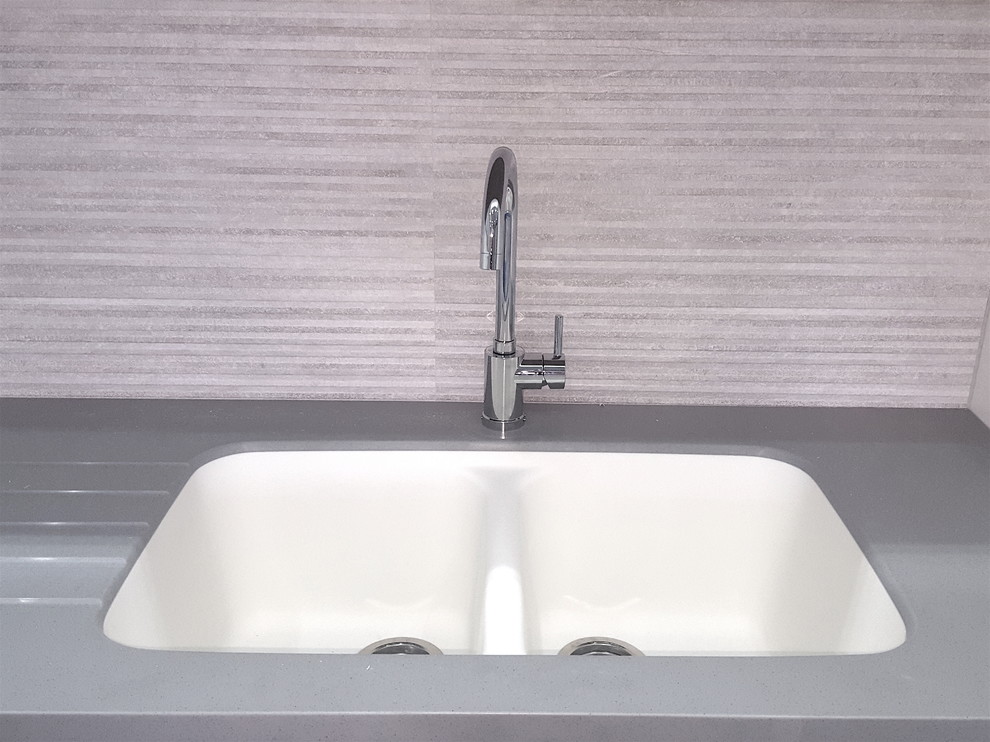 Inspiration for a large modern l-shaped ceramic tile kitchen pantry remodel with an integrated sink, flat-panel cabinets, white cabinets, ceramic backsplash, black appliances and an island