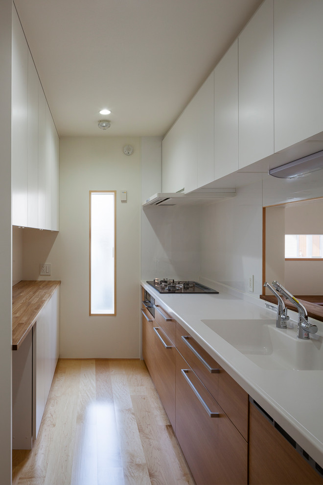 Geschlossene, Zweizeilige, Mittelgroße Küche mit braunen Schränken, Mineralwerkstoff-Arbeitsplatte, Küchenrückwand in Weiß, Rückwand aus Glasfliesen, weißen Elektrogeräten, hellem Holzboden und weißer Arbeitsplatte in Tokio