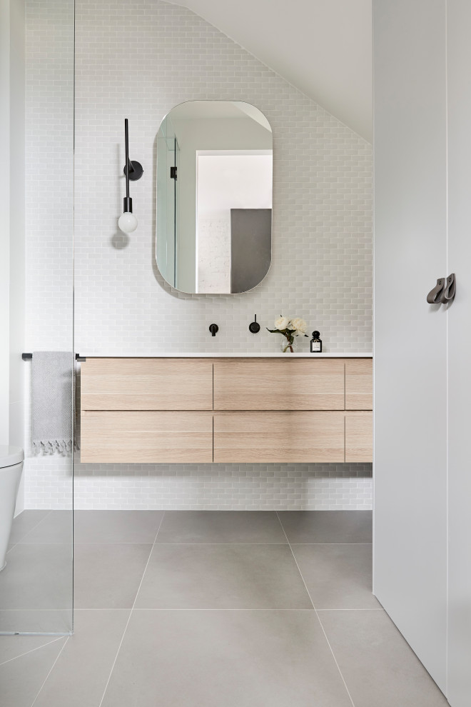 This is an example of a contemporary bathroom in Melbourne with flat-panel cabinets, light wood cabinets, white tile, mosaic tile, white walls, an undermount sink, grey floor, white benchtops, a single vanity, a floating vanity and vaulted.