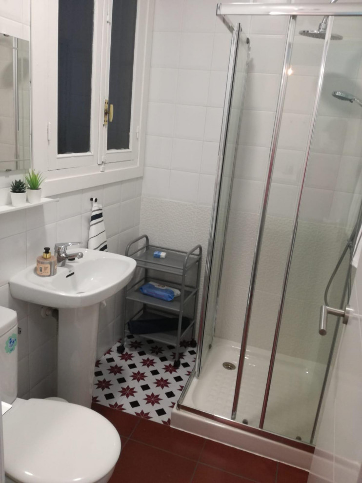 Photo of a powder room in Madrid with multi-coloured tile, white walls and red floor.