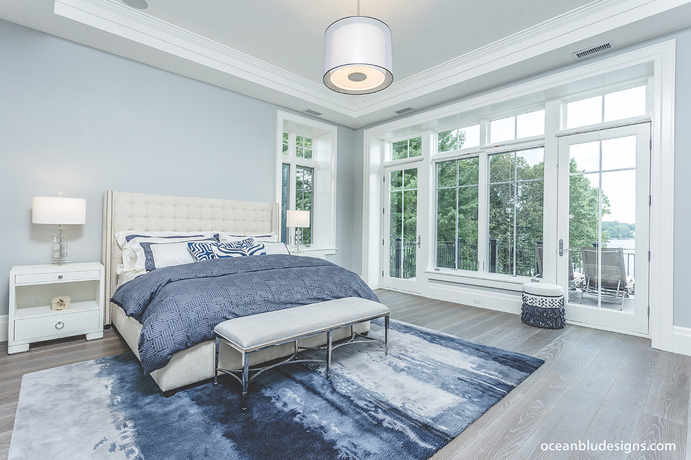Large contemporary master bedroom in New York with blue walls and medium hardwood floors.