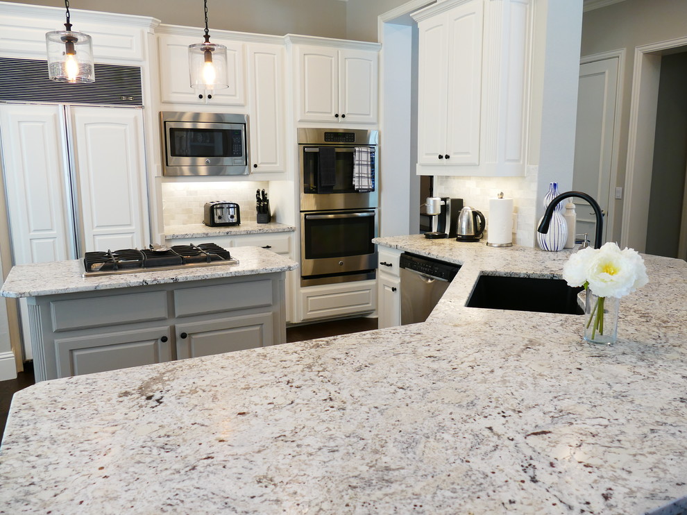 Example of a mid-sized transitional u-shaped dark wood floor and brown floor open concept kitchen design with an undermount sink, raised-panel cabinets, white cabinets, granite countertops, beige backsplash, stone tile backsplash and stainless steel appliances