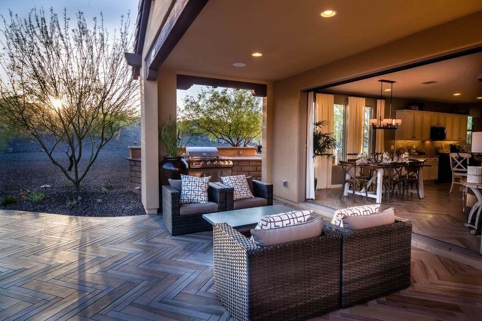 This is an example of a mid-sized contemporary backyard patio in Phoenix with an outdoor kitchen and a roof extension.
