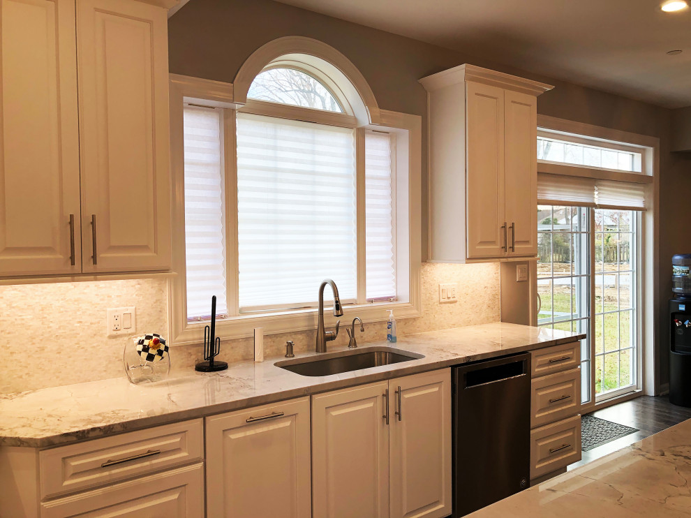 Inspiration for a large traditional u-shaped kitchen in Baltimore with an undermount sink, raised-panel cabinets, white cabinets, quartzite benchtops, grey splashback, ceramic splashback, stainless steel appliances, laminate floors, with island, brown floor and yellow benchtop.
