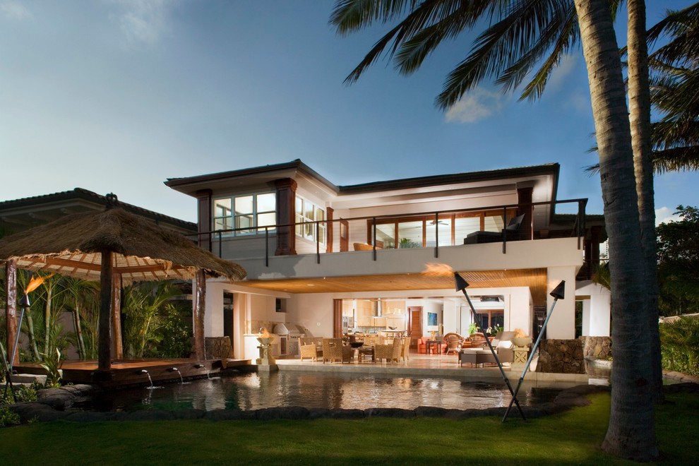 This is an example of a large tropical two-storey beige exterior in Hawaii with stone veneer.