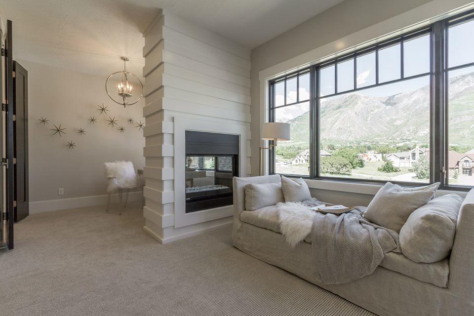 Photo of a large transitional master bedroom in Salt Lake City with grey walls, carpet, a two-sided fireplace, a wood fireplace surround and beige floor.