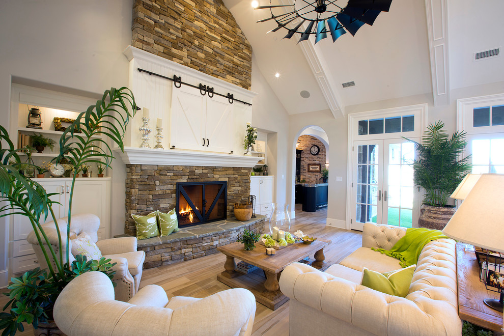 Photo of a large country formal open concept living room in Dallas with white walls, light hardwood floors, a standard fireplace, a brick fireplace surround, a concealed tv and beige floor.