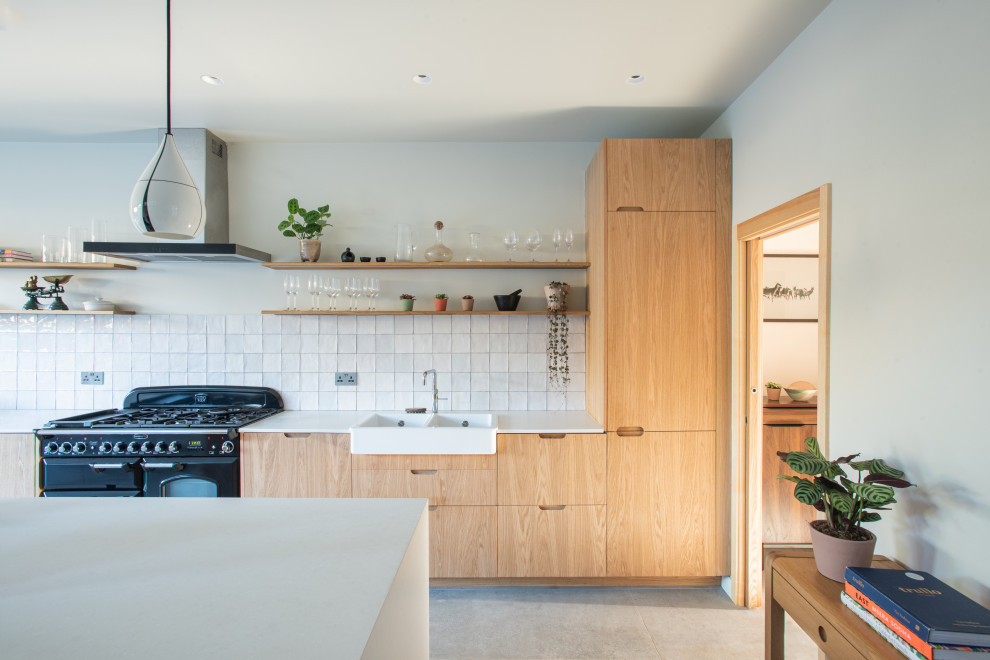 Design ideas for a mid-sized scandinavian single-wall eat-in kitchen in London with a double-bowl sink, flat-panel cabinets, medium wood cabinets, solid surface benchtops, white splashback, ceramic splashback, black appliances, porcelain floors, with island, grey floor and white benchtop.