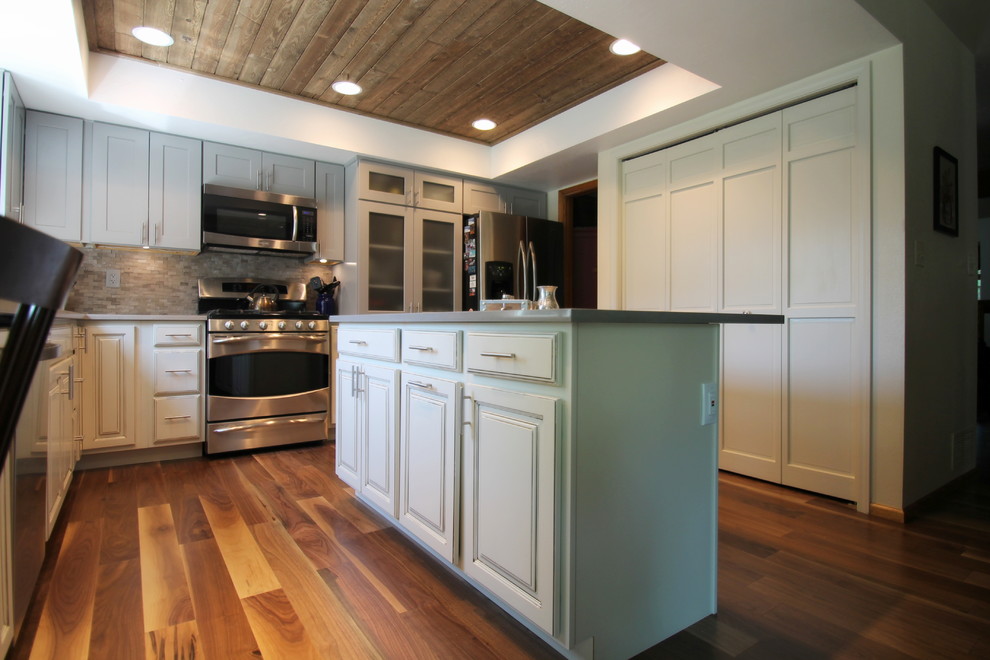 Example of a large transitional l-shaped medium tone wood floor eat-in kitchen design in Denver with an undermount sink, shaker cabinets, gray cabinets, quartz countertops, gray backsplash, stone tile backsplash, stainless steel appliances and an island