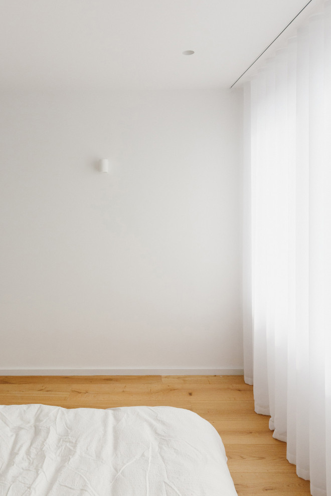 Mittelgroßes Modernes Schlafzimmer mit weißer Wandfarbe und braunem Holzboden in Manchester