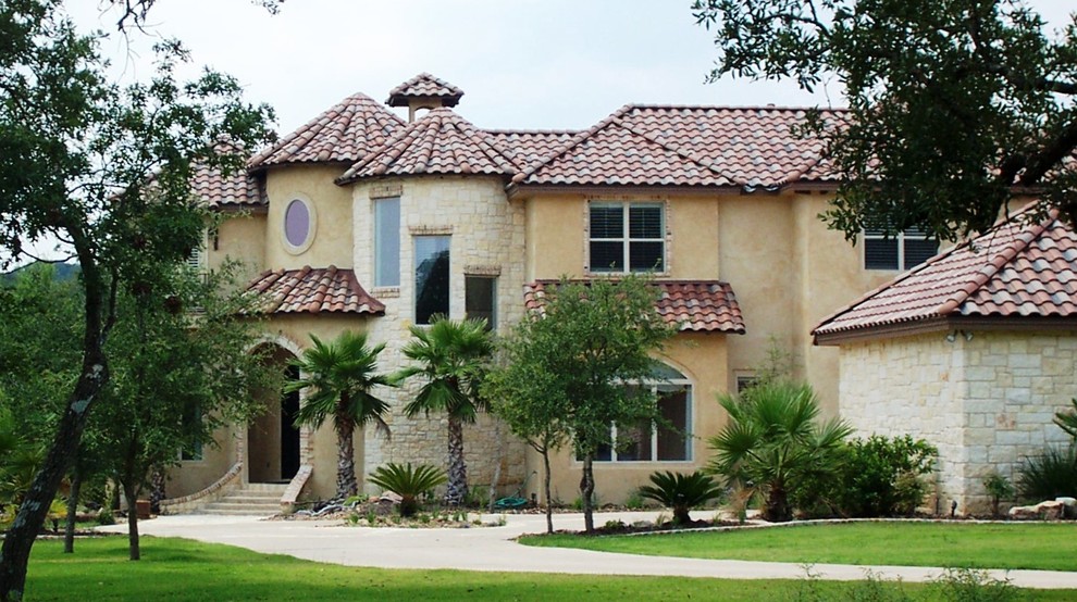 This is an example of a large mediterranean two-storey beige exterior in Austin with stone veneer.