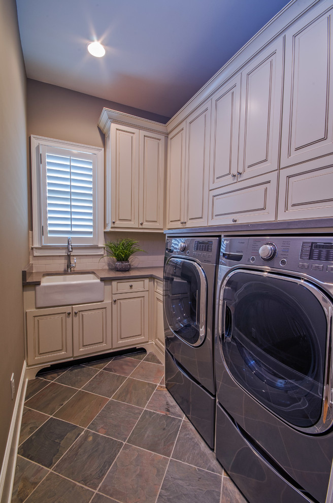 Photo of a mid-sized transitional l-shaped laundry room in Atlanta with a farmhouse sink, raised-panel cabinets, beige cabinets, brown walls, porcelain floors and a side-by-side washer and dryer.