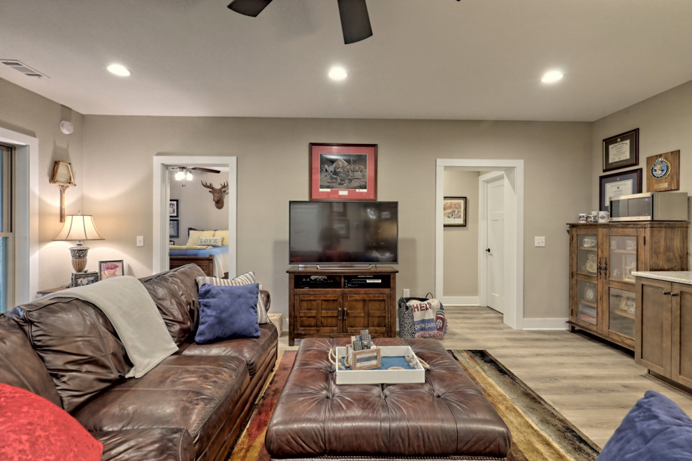 Immagine di un grande soggiorno american style aperto con pareti beige, pavimento in vinile, nessun camino, TV autoportante e pavimento marrone