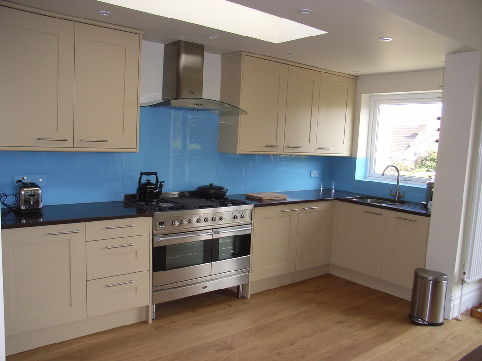 Photo of a mid-sized contemporary l-shaped eat-in kitchen in Other with an undermount sink, shaker cabinets, beige cabinets, quartzite benchtops, blue splashback, glass sheet splashback, stainless steel appliances and light hardwood floors.