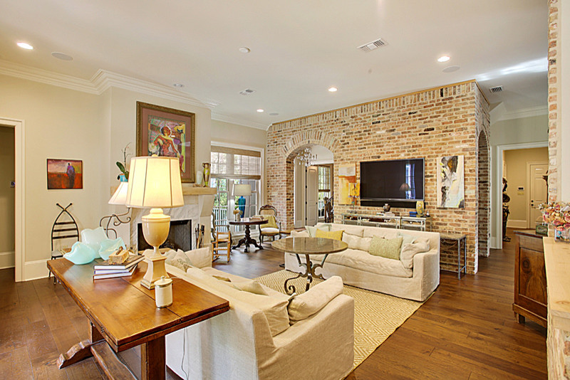Photo of a mid-sized arts and crafts open concept living room in New Orleans with beige walls, medium hardwood floors, a standard fireplace, a tile fireplace surround and a wall-mounted tv.