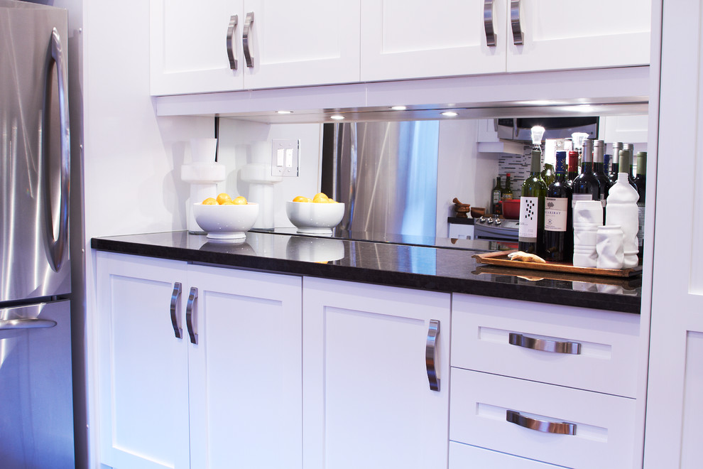 Example of a mid-sized transitional galley dark wood floor enclosed kitchen design in Toronto with shaker cabinets, white cabinets, granite countertops, stainless steel appliances, a double-bowl sink, multicolored backsplash and matchstick tile backsplash