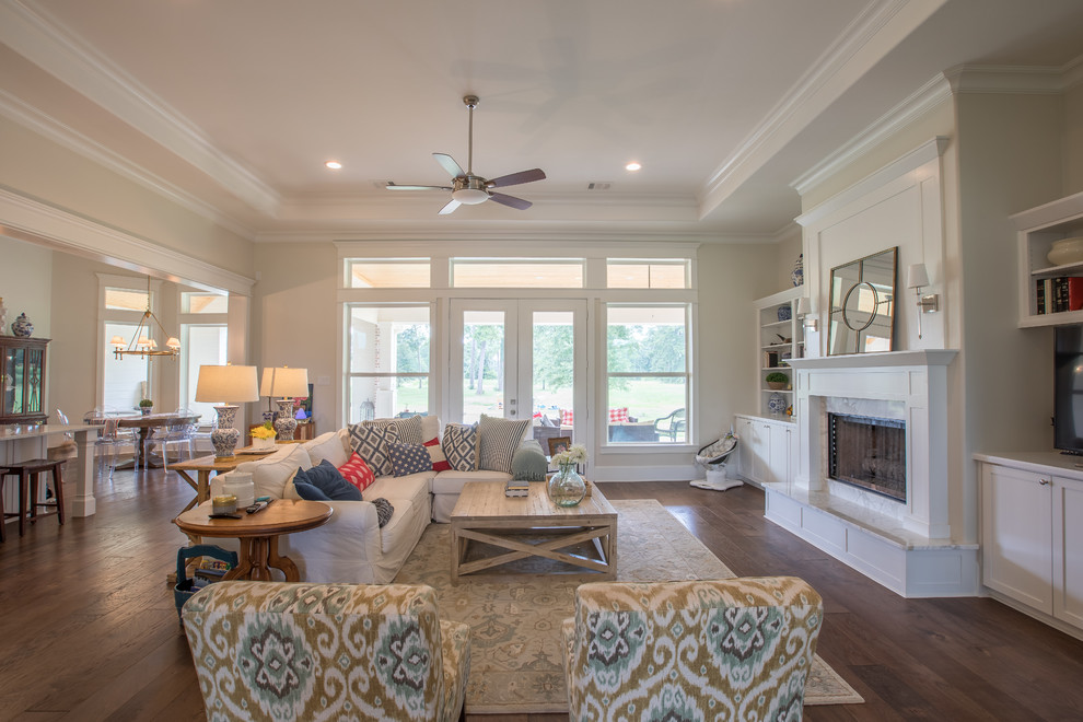 Photo of a large traditional open concept family room in Houston with beige walls, dark hardwood floors, a standard fireplace, a stone fireplace surround, a freestanding tv and brown floor.