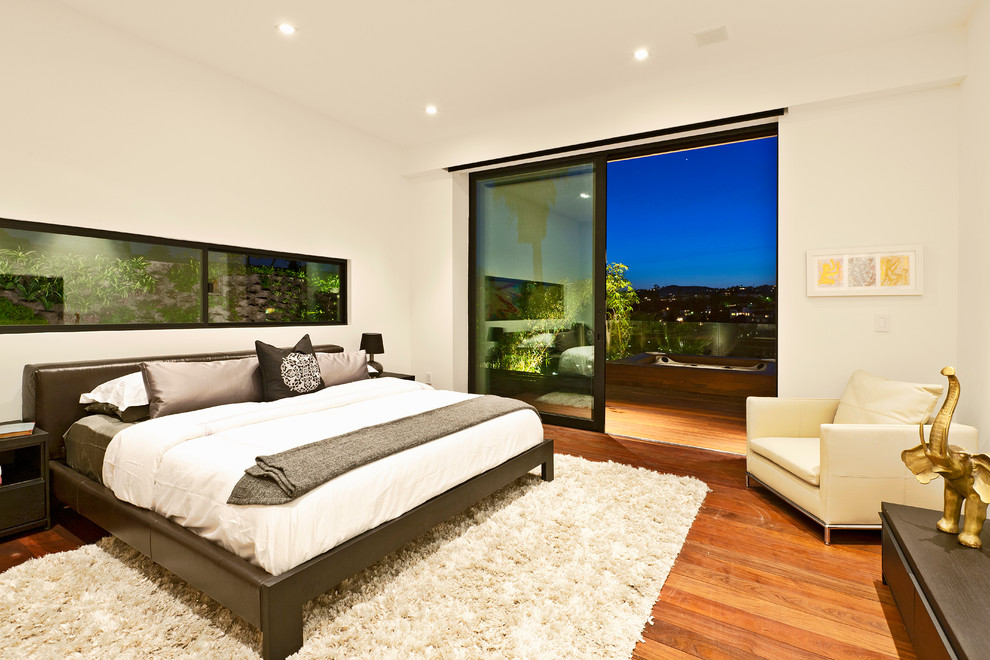 Photo of a contemporary bedroom in Los Angeles with white walls and medium hardwood floors.