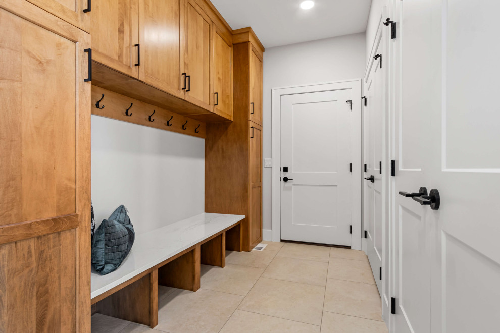 Example of a mid-sized transitional porcelain tile and beige floor mudroom design with white walls and a white front door