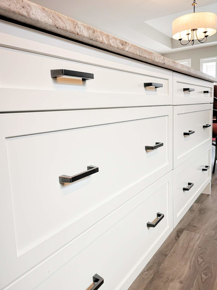 Inspiration for a mid-sized transitional l-shaped medium tone wood floor and brown floor open concept kitchen remodel in Toronto with an undermount sink, shaker cabinets, light wood cabinets, granite countertops, white backsplash, porcelain backsplash, stainless steel appliances, an island and beige countertops