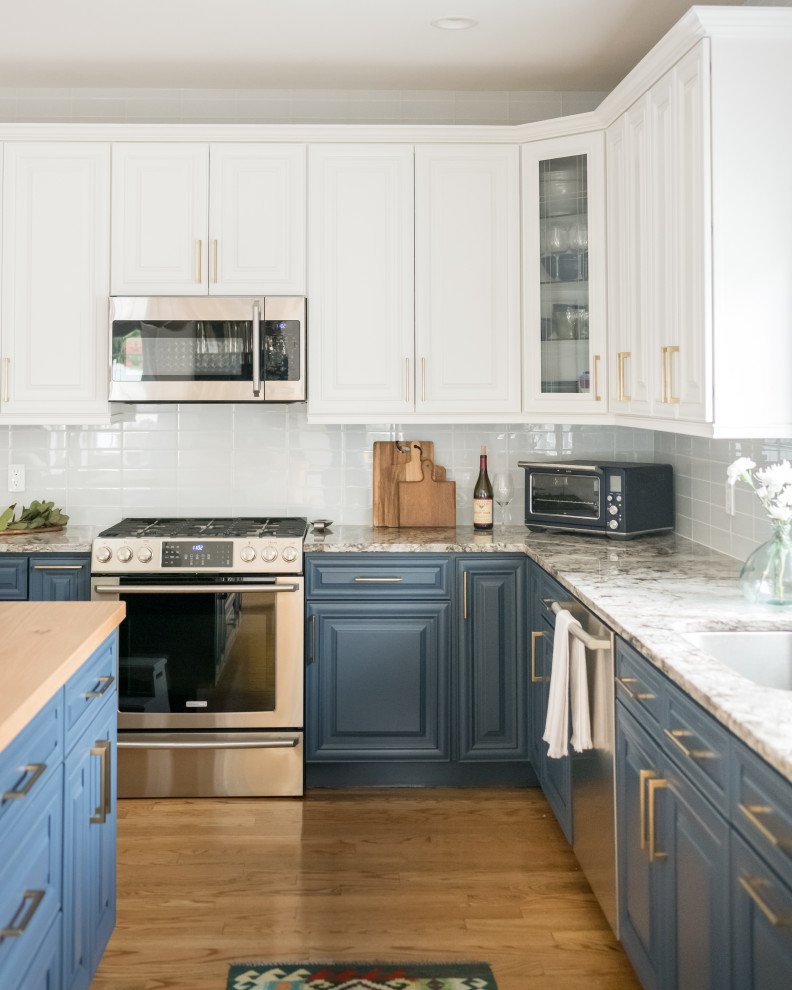Inspiration for a large transitional l-shaped medium tone wood floor eat-in kitchen remodel in Boston with a drop-in sink, raised-panel cabinets, blue cabinets, wood countertops, gray backsplash, ceramic backsplash, stainless steel appliances and an island