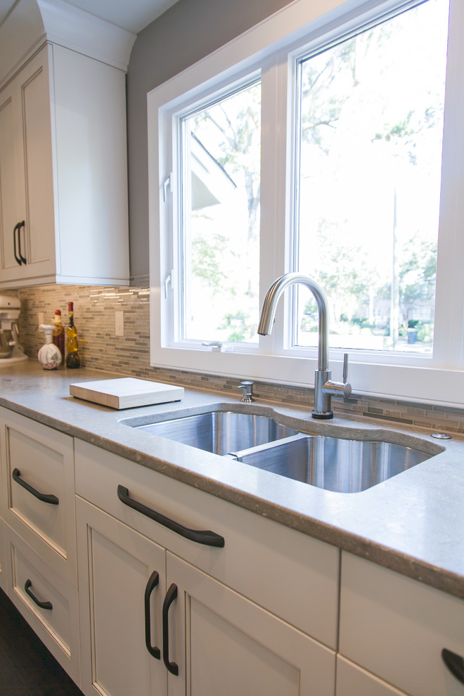 Inspiration for a large transitional u-shaped dark wood floor enclosed kitchen remodel in Charleston with an undermount sink, white cabinets, marble countertops, brown backsplash, stainless steel appliances and an island