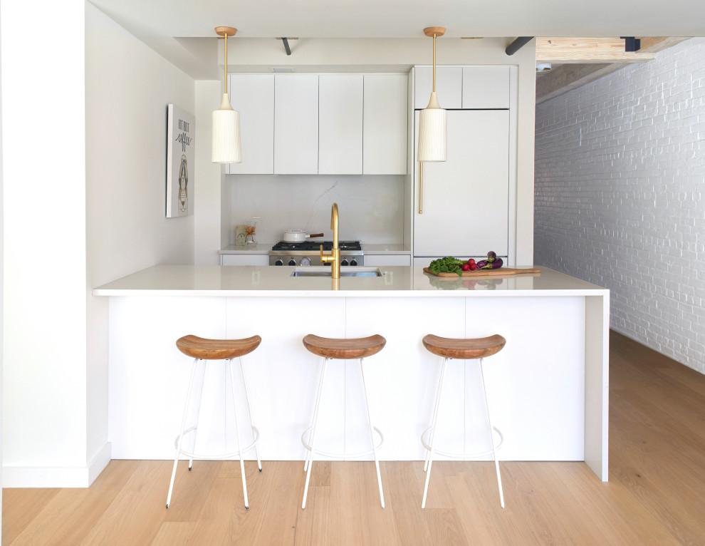 Small urban light wood floor and exposed beam kitchen photo with a drop-in sink, flat-panel cabinets, white cabinets, marble countertops, white backsplash, marble backsplash, paneled appliances, an island and white countertops