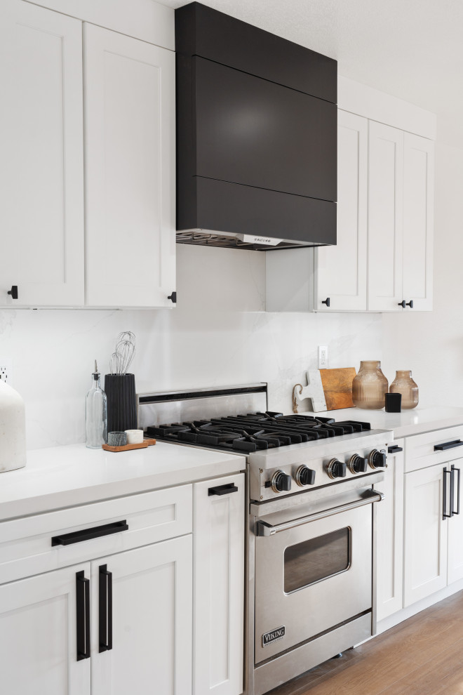 Mid-sized transitional vinyl floor and brown floor open concept kitchen photo in Orange County with an undermount sink, shaker cabinets, white cabinets, quartz countertops, white backsplash, quartz backsplash, stainless steel appliances, an island and white countertops