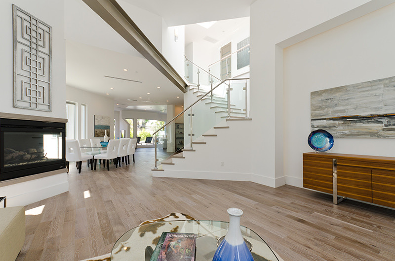 Photo of a large contemporary wood u-shaped staircase in Los Angeles with wood risers and glass railing.