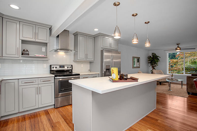 Example of a transitional medium tone wood floor eat-in kitchen design in Seattle with raised-panel cabinets, gray cabinets, quartzite countertops, white backsplash, glass tile backsplash, stainless steel appliances and an island