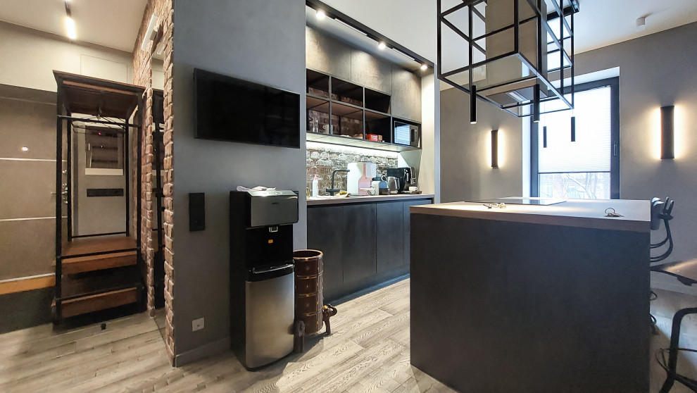 Inspiration for a large industrial galley eat-in kitchen in Moscow with an undermount sink, flat-panel cabinets, black cabinets, wood benchtops, brown splashback, brick splashback, stainless steel appliances, medium hardwood floors, with island, brown floor and brown benchtop.