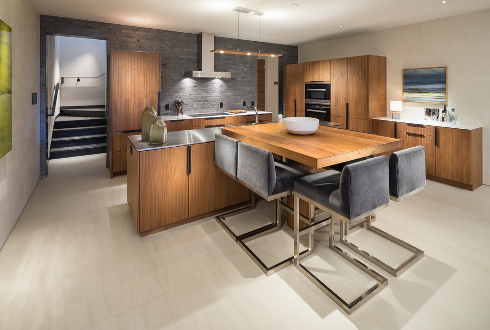 Photo of an expansive contemporary l-shaped eat-in kitchen in Salt Lake City with flat-panel cabinets, medium wood cabinets, stainless steel benchtops, grey splashback, panelled appliances, with island, beige floor and grey benchtop.