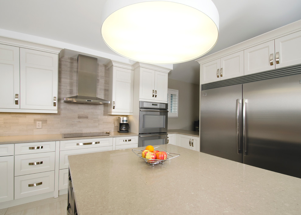 Transitional u-shaped limestone floor eat-in kitchen photo with an undermount sink, raised-panel cabinets, gray cabinets, quartz countertops, beige backsplash, stone tile backsplash, stainless steel appliances and an island
