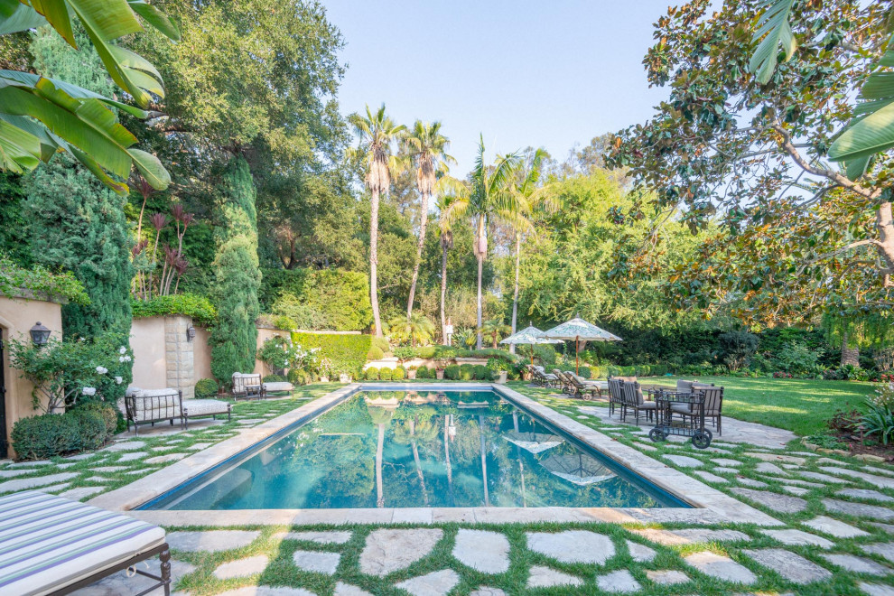 Идея дизайна: огромный прямоугольный ландшафтный бассейн на заднем дворе в средиземноморском стиле с покрытием из каменной брусчатки