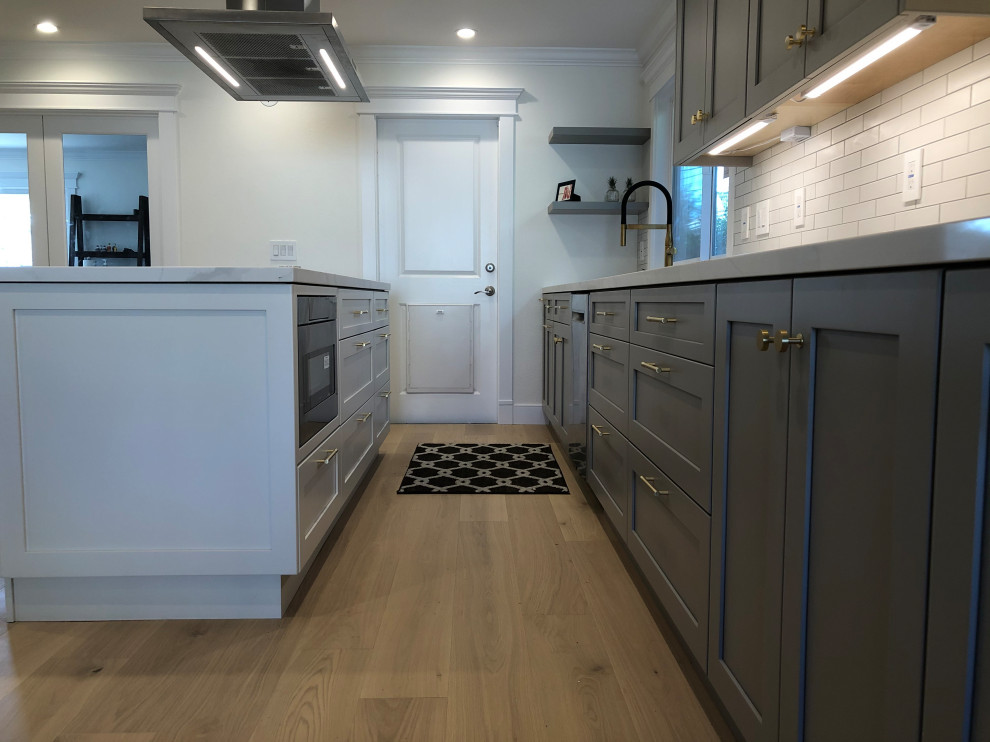Example of a mid-sized transitional galley medium tone wood floor and beige floor eat-in kitchen design in San Francisco with an undermount sink, recessed-panel cabinets, gray cabinets, quartz countertops, white backsplash, ceramic backsplash, stainless steel appliances, an island and white countertops