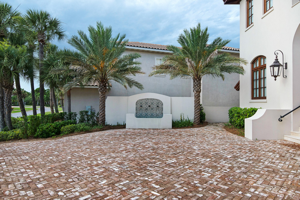 Design ideas for a large mediterranean front yard partial sun driveway in Miami with a water feature and brick pavers.