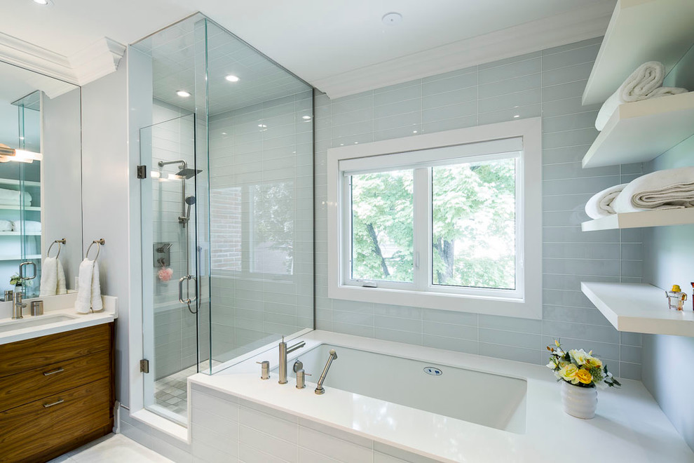 This is an example of a mid-sized modern master bathroom in Toronto with flat-panel cabinets, dark wood cabinets, an undermount tub, a corner shower, blue walls, marble floors, an undermount sink, engineered quartz benchtops, glass tile, white floor and a hinged shower door.