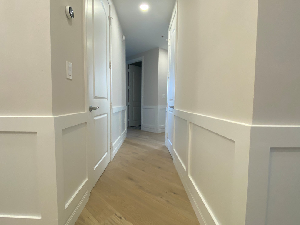 Large contemporary hallway in Miami with white walls, light hardwood floors, multi-coloured floor, recessed and decorative wall panelling.