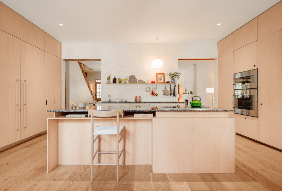This is an example of a large contemporary u-shaped eat-in kitchen in Toronto with an undermount sink, flat-panel cabinets, light wood cabinets, granite benchtops, white splashback, panelled appliances, light hardwood floors and with island.