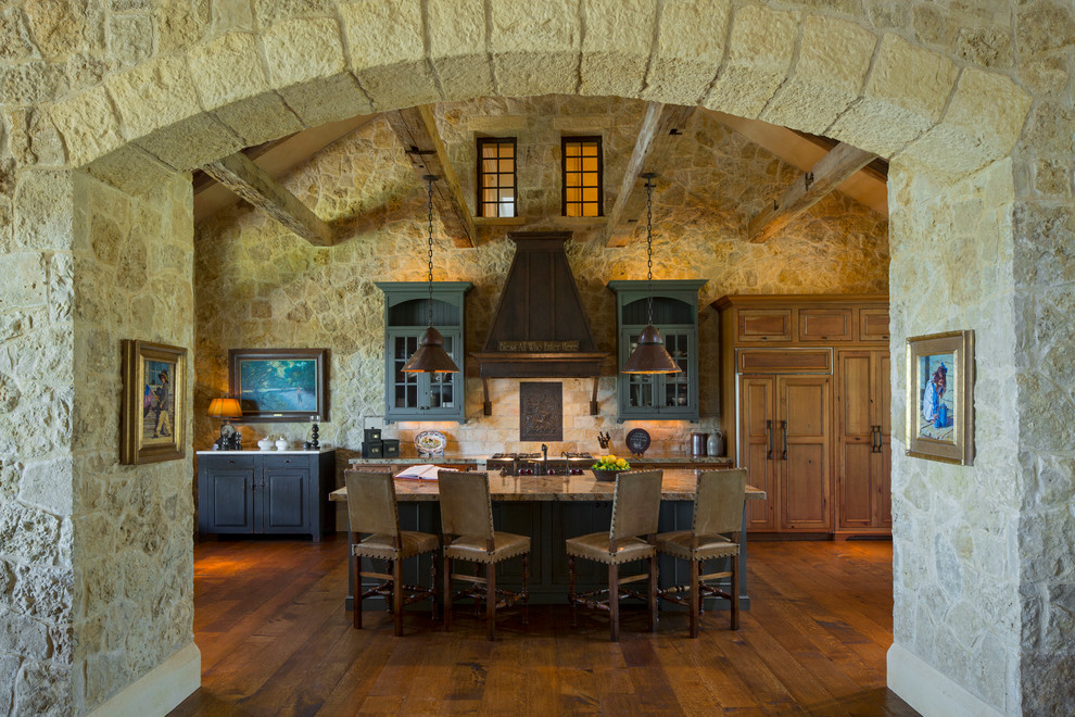Inspiration for a large rustic single-wall medium tone wood floor open concept kitchen remodel in Austin with glass-front cabinets, distressed cabinets, stone tile backsplash and an island