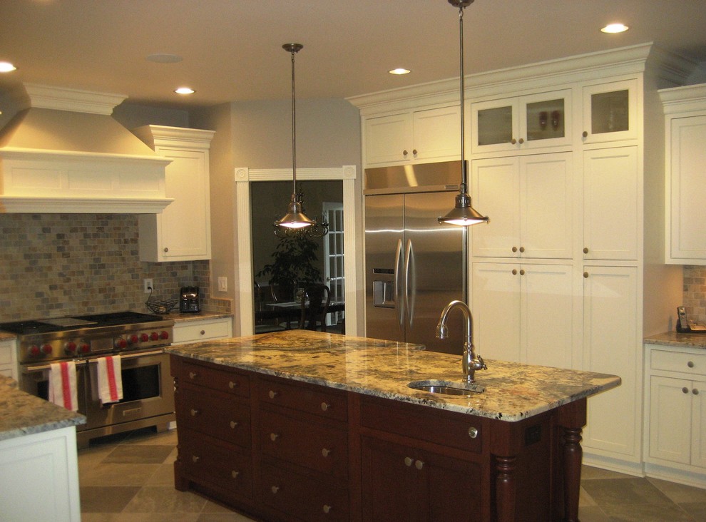 Kitchen - transitional l-shaped porcelain tile kitchen idea with white cabinets, stone tile backsplash, stainless steel appliances, an island, an undermount sink and granite countertops