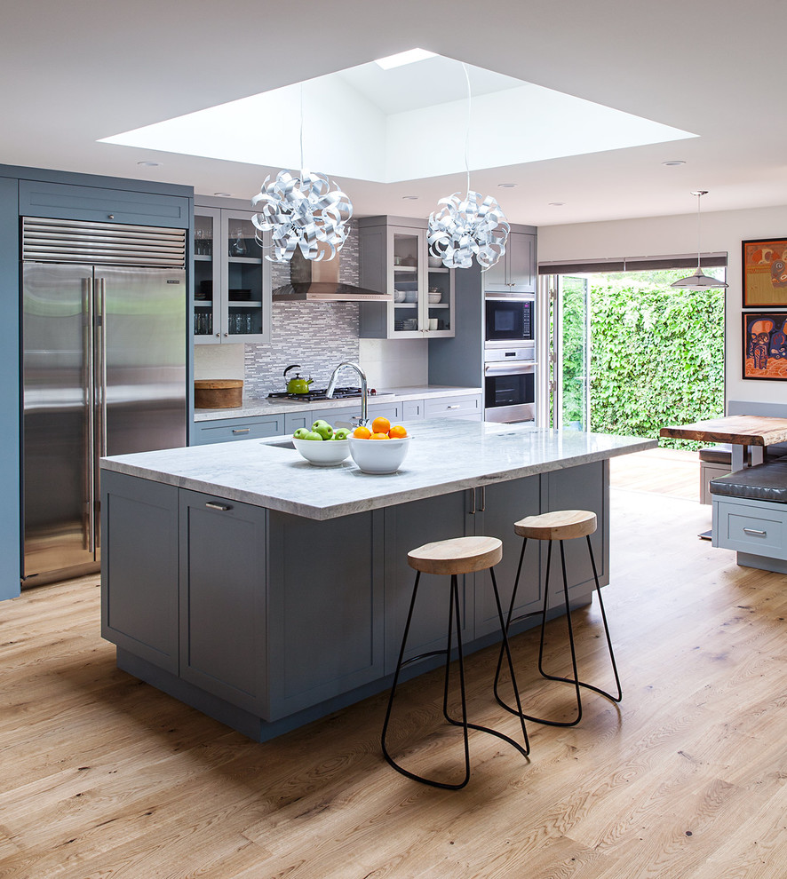 This is an example of an expansive modern single-wall open plan kitchen in San Francisco with an undermount sink, shaker cabinets, blue cabinets, quartzite benchtops, multi-coloured splashback, porcelain splashback, stainless steel appliances, medium hardwood floors and with island.