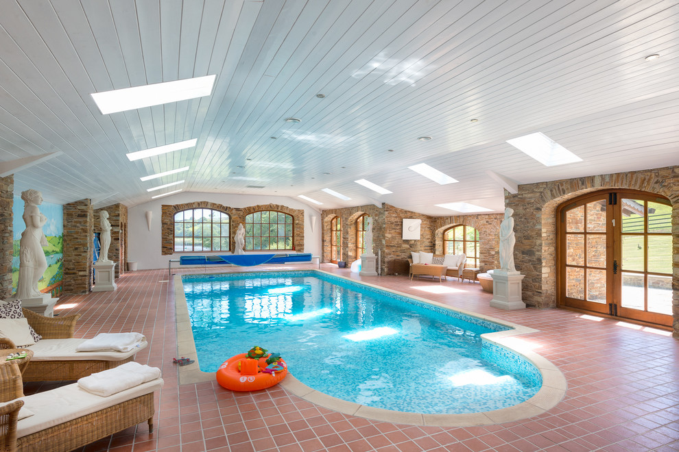 Expansive country indoor custom-shaped pool in Devon with tile.